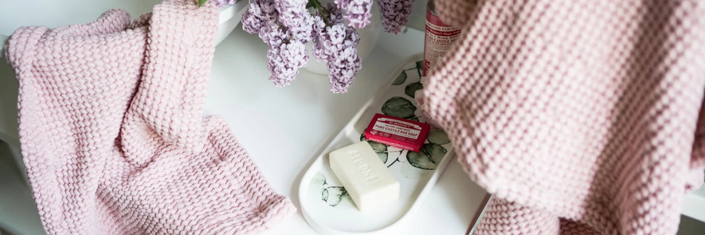 Pink linen waffle bath towels styled with fresh lilacs and natural soap for a luxury bathroom ritual.